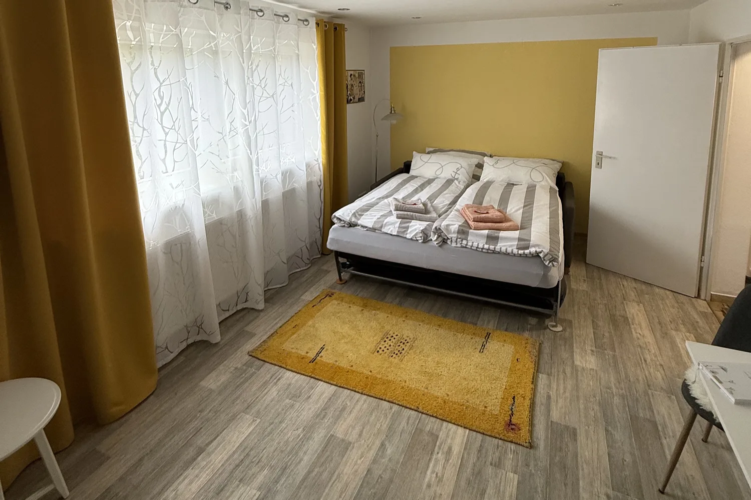 Wohn- und Schlafzimmer der Casa Billa mit Doppelbett und hellen Vorhängen